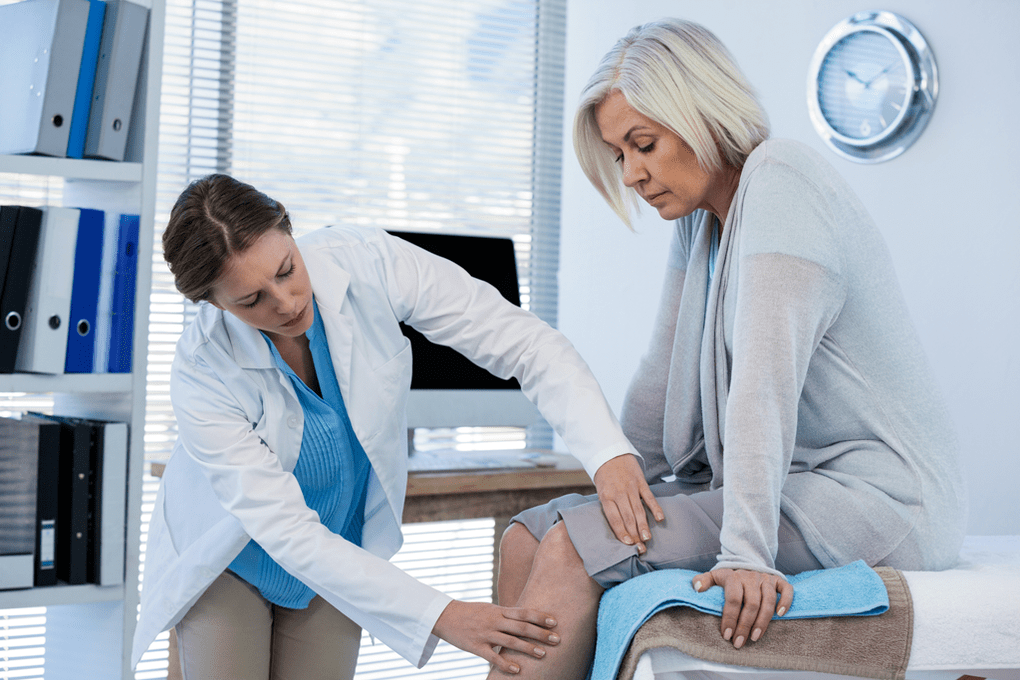 An arthrosis patient who needs therapy is examined by a doctor